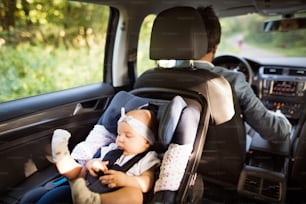 Unrecognizable man driving with a baby girl in car seat.