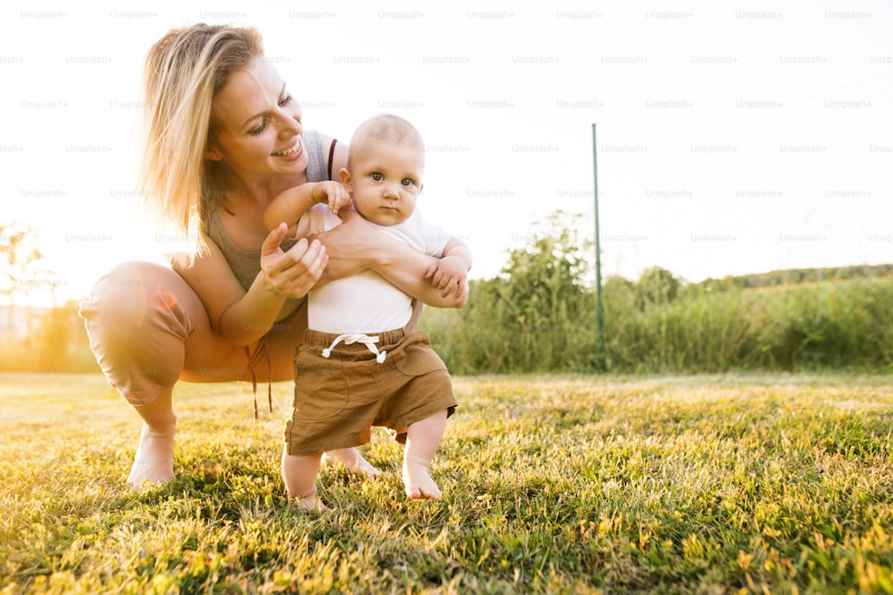 Beautiful young mother with her baby son. First steps.