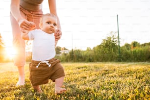 Unrecognizable young mother with her baby son. First steps.