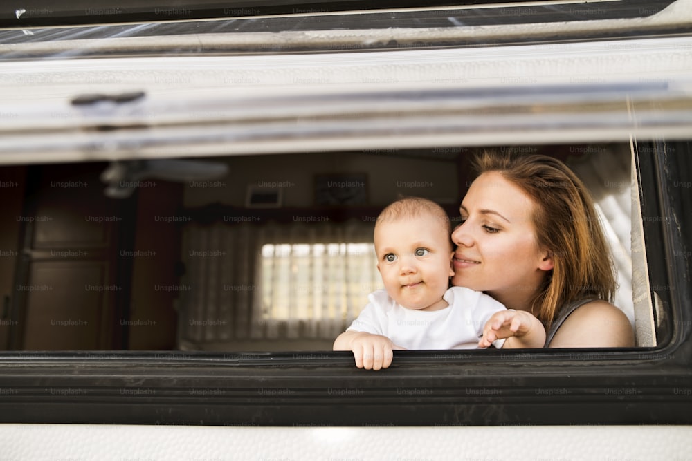 Hermosa madre joven y su hijo pequeño en una autocaravana en un día de verano.