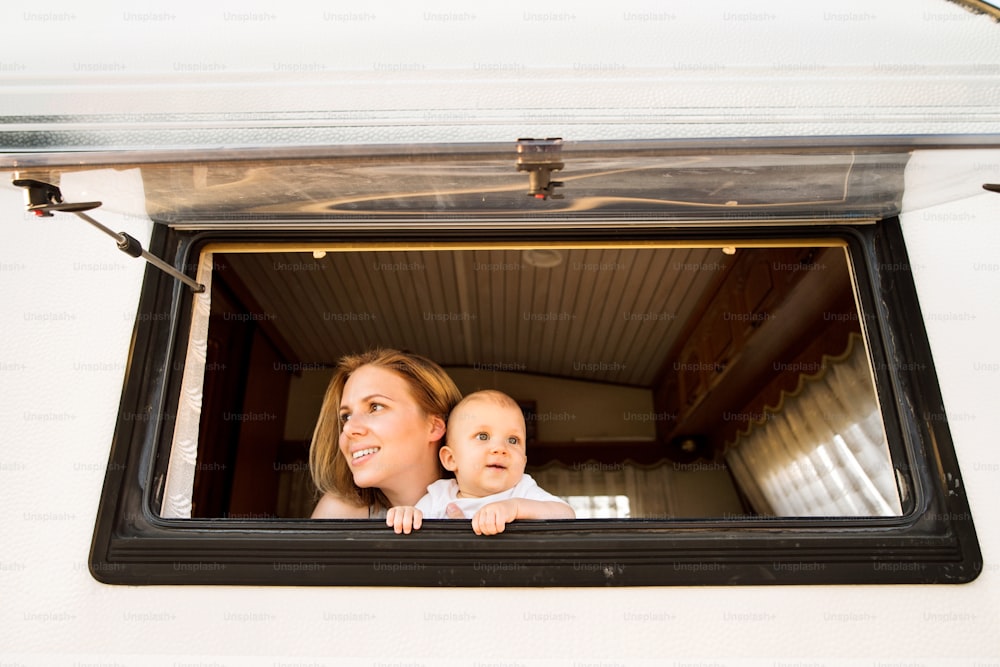 夏の日にキャンピングカーに乗る美しい若い母親と赤ん坊の息子