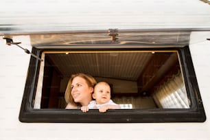 Bela jovem mãe e seu filho bebê em uma van campista em um dia de verão