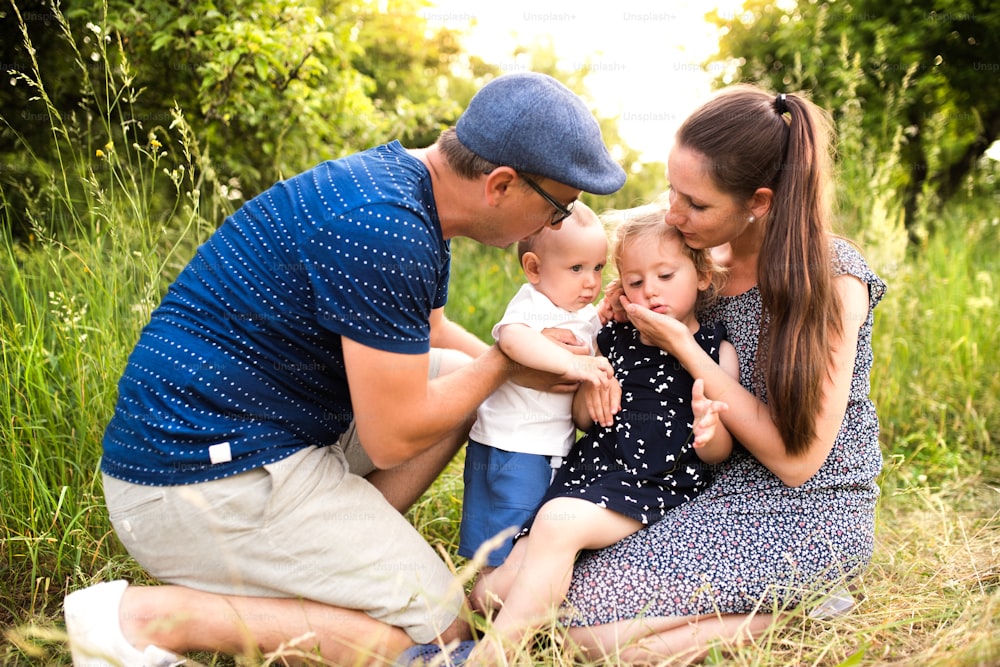 Familia joven feliz con niños pequeños que pasan tiempo juntos al aire libre en la naturaleza verde del verano
