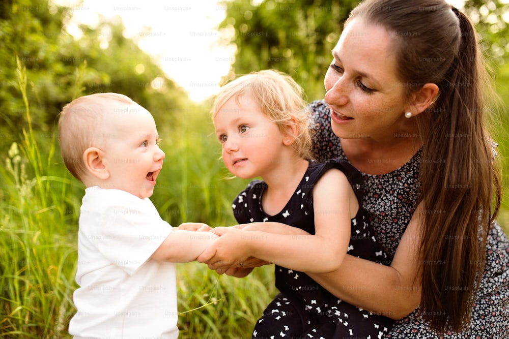 Belle jeune mère avec de petits enfants passant du temps ensemble à l’extérieur dans la nature verte de l’été