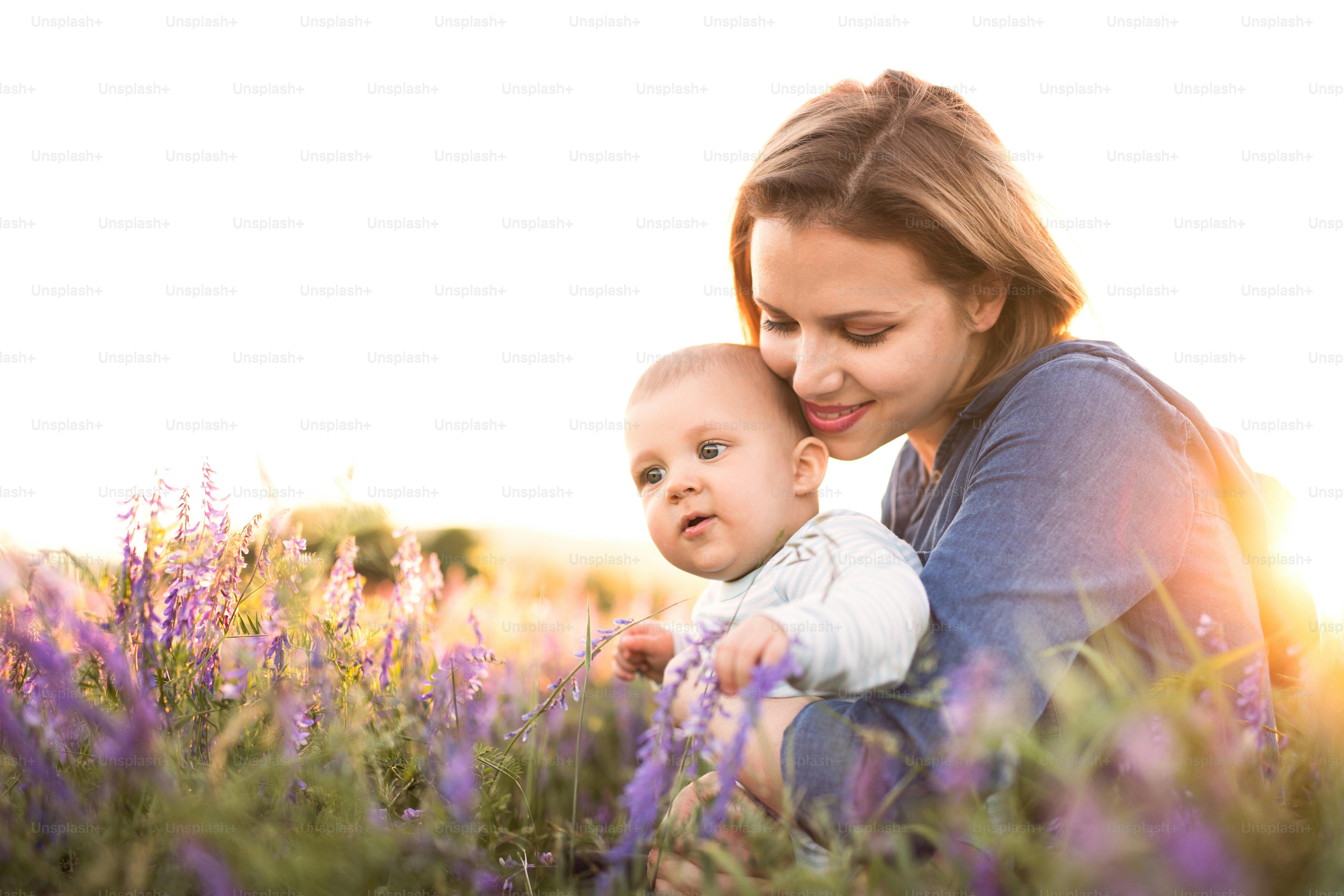 Ibu muda yang cantik menggendong bayi laki-lakinya yang masih kecil di pelukan di luar ruangan di alam di ladang lavender.