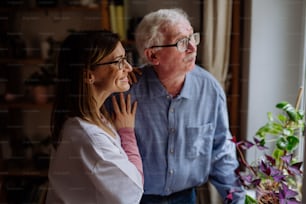 A healthcare worker or caregiver visiting senior man indoors at home, talking.