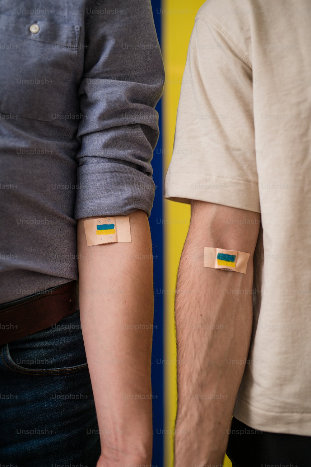 Blood donors with a bandage after giving blood on Ukrainian flag background.