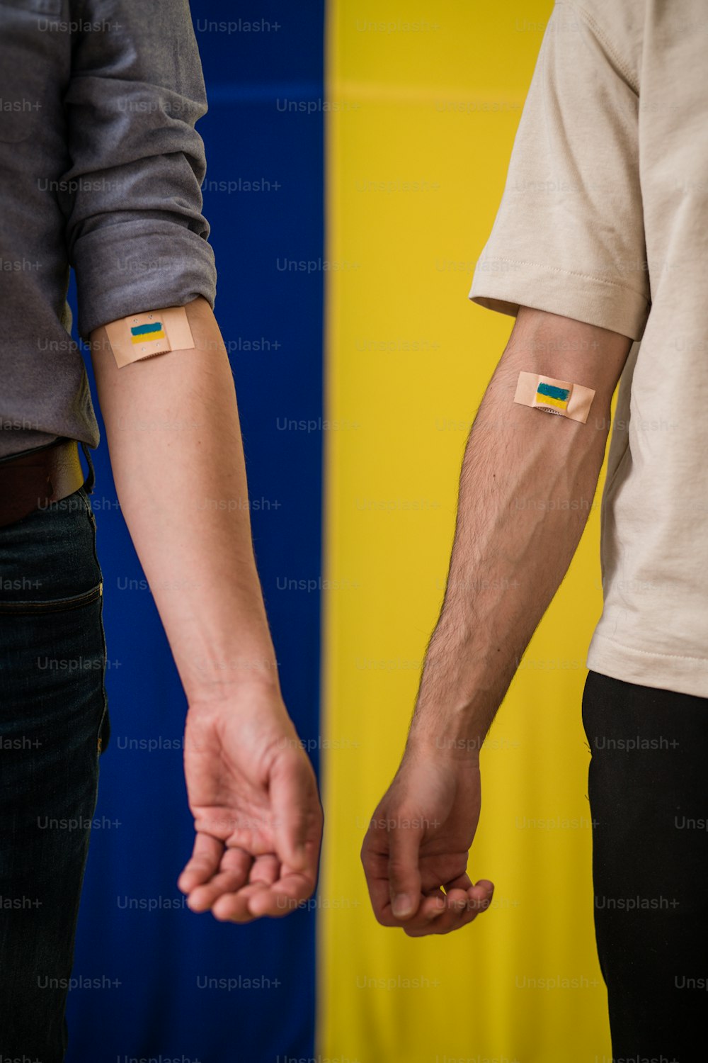 Blood donors with a bandage after giving blood on Ukrainian flag background.