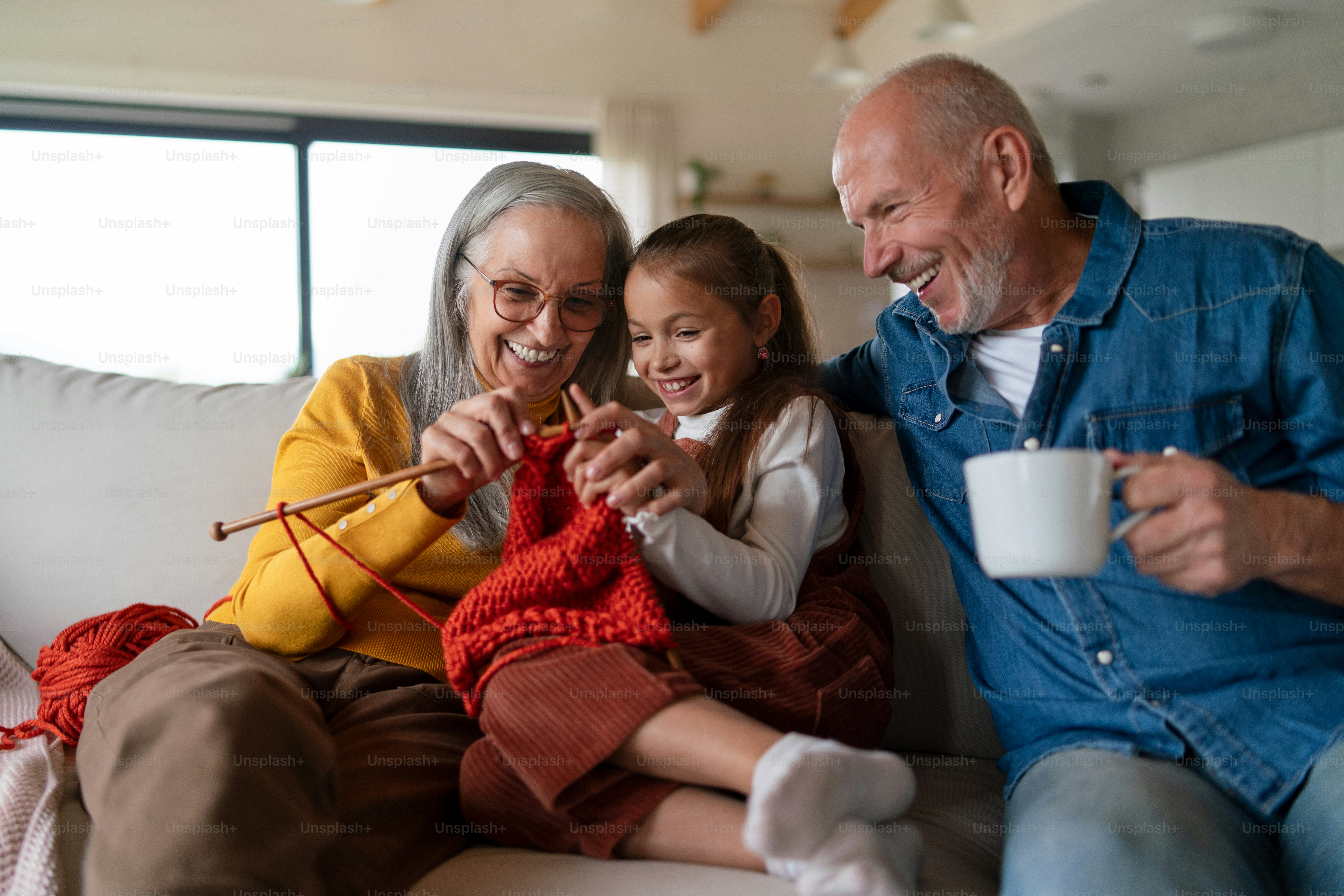 Foto Una niña sentada en el sofá con sus abuelos y aprendiendo a tejer ...