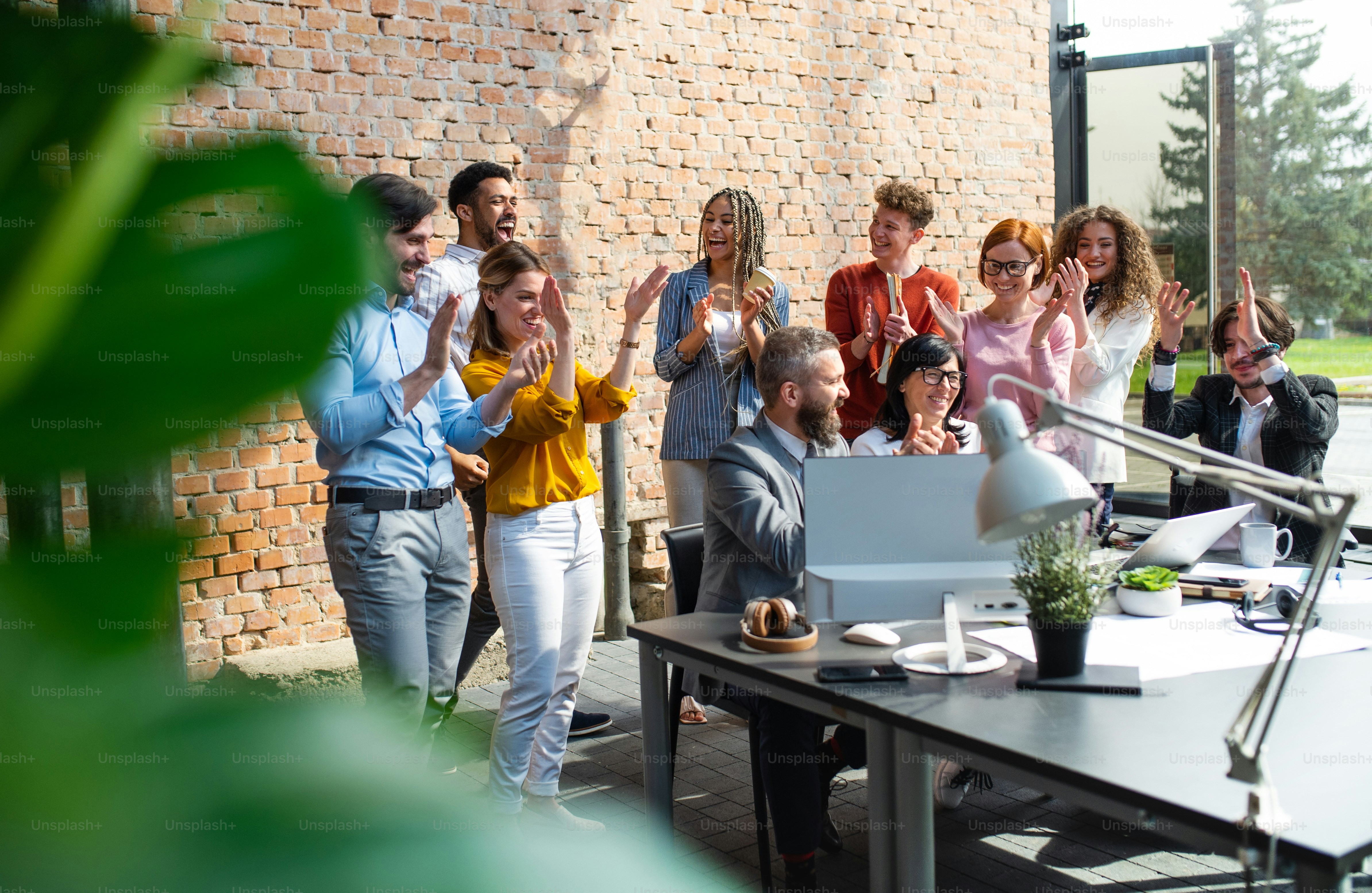Eine Gruppe begeisterter Unternehmer, die drinnen im Büro an einem Projekt arbeiten und einen erfolgreichen Vertrag feiern.