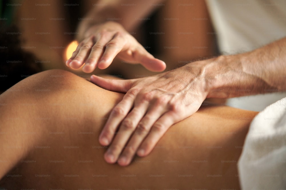 Giovane donna irriconoscibile che fa un massaggio rilassante alla schiena presso il centro benessere.