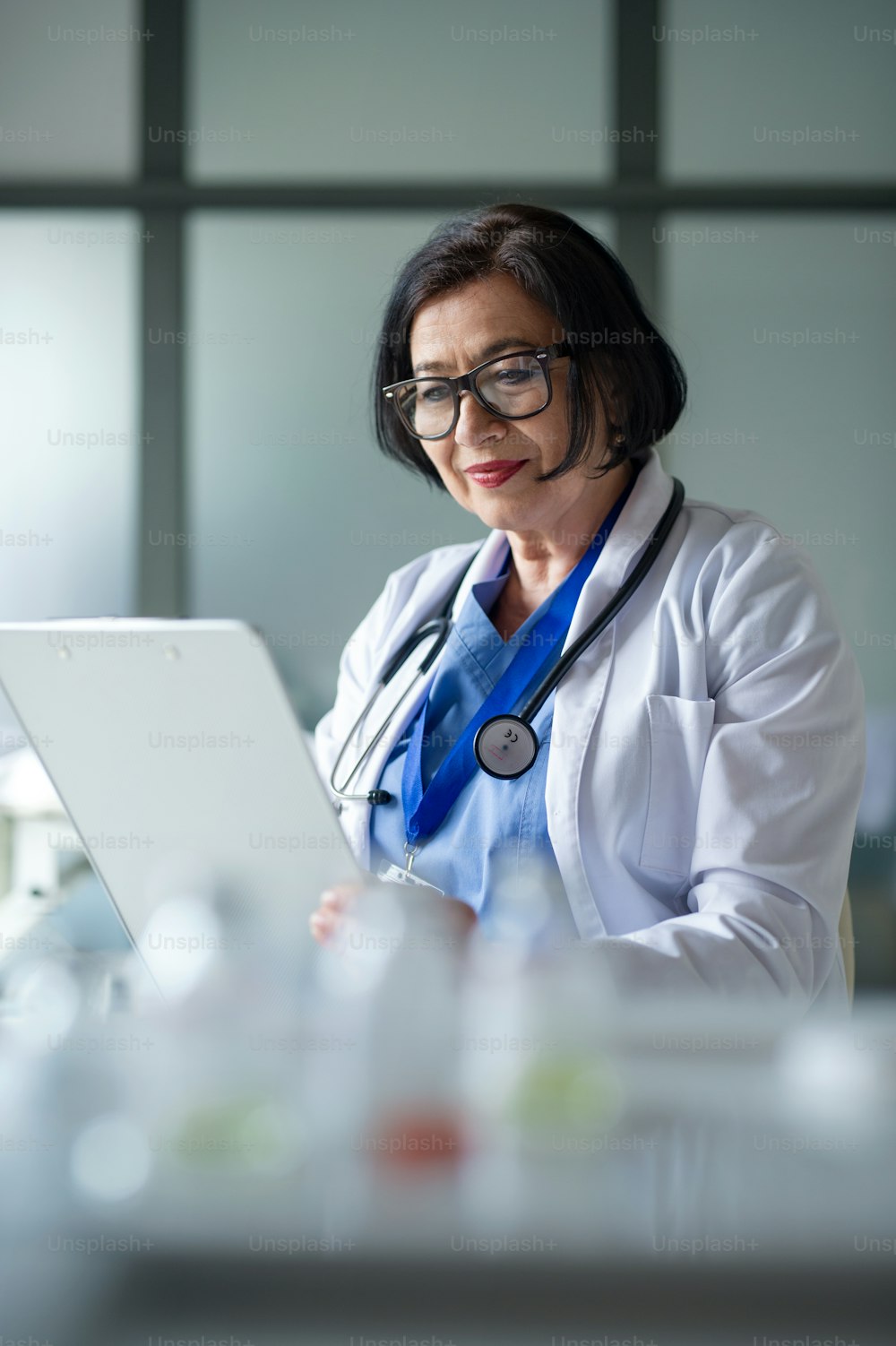 A portrait of senior woman doctor in hospital, using tablet.