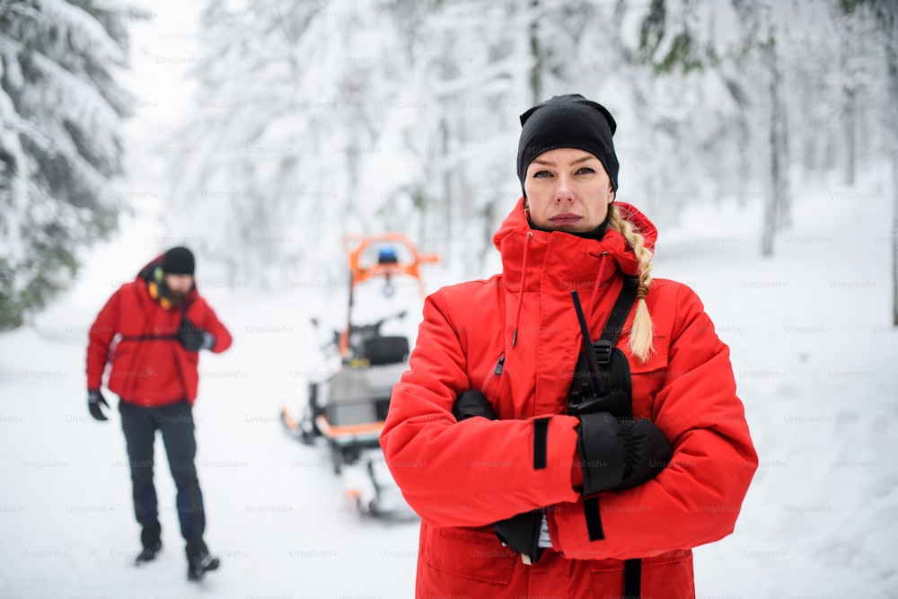 겨울철 숲에서 야외에서 산악 구조대원의 여성 구급대원이 카메라를 보고 있다.