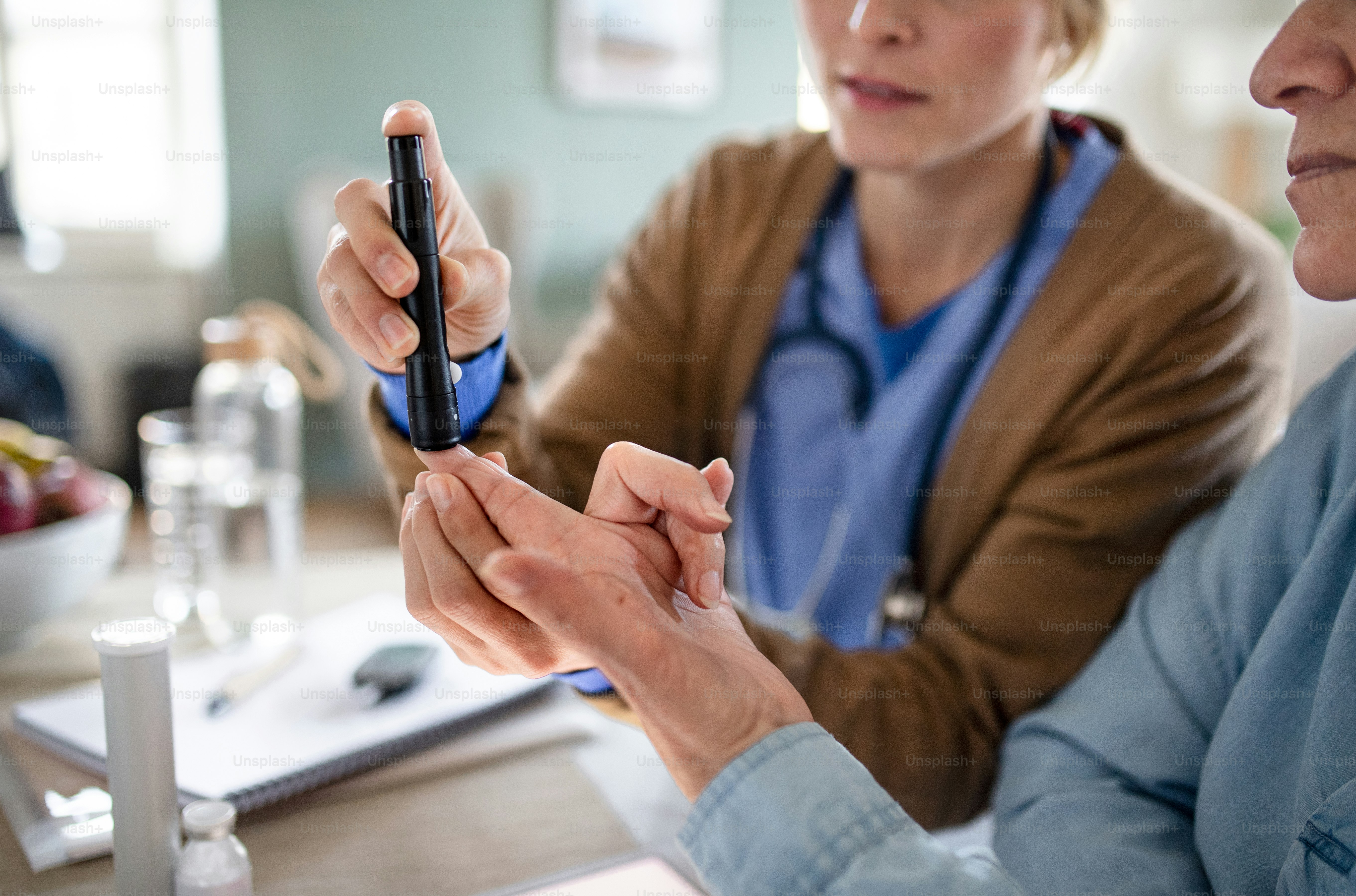 Mittelteil der Krankenschwester, des Pflegepersonals oder des Gesundheitspersonals mit einer älteren Patientin, die den Blutzucker in Innenräumen misst.