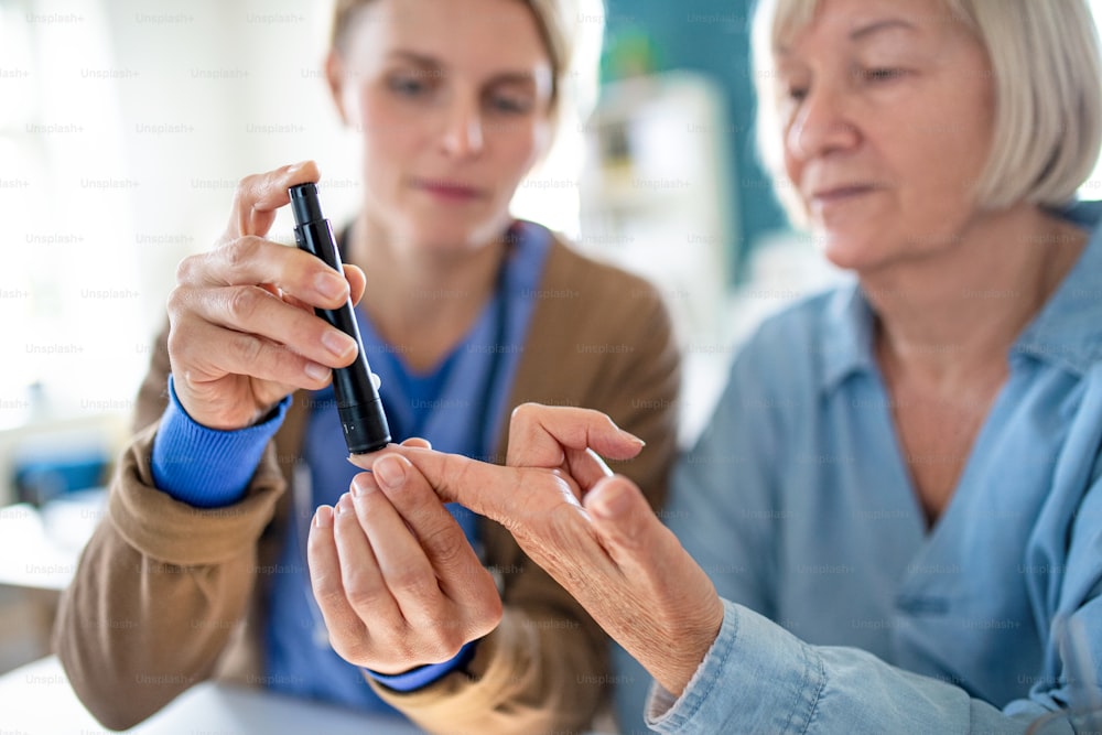 Nurse, caregiver or healthcare worker with senior woman patient, measuring blood glucose indoors.