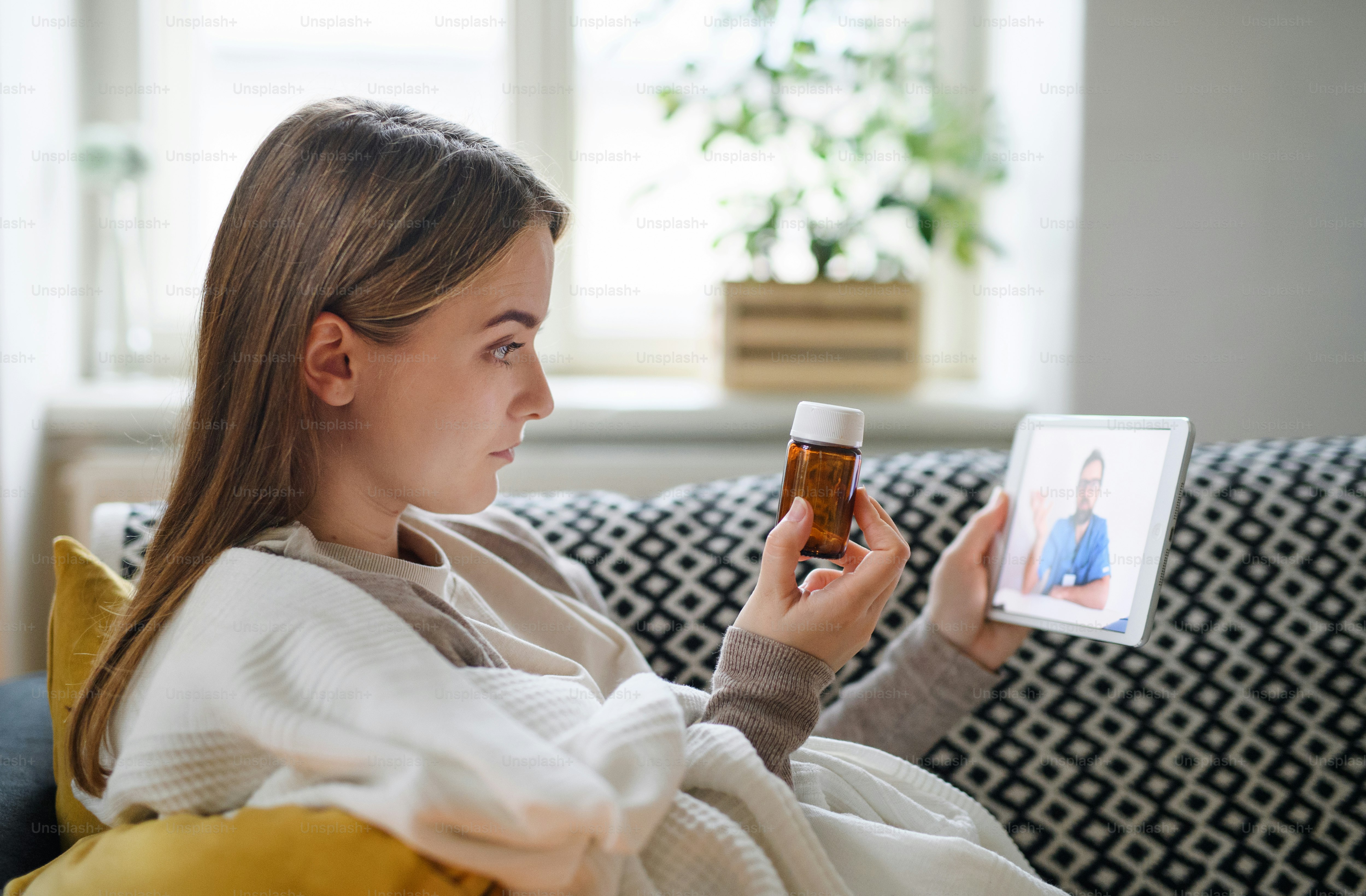 Ill young woman having video call with doctor on tablet at home, online consultation concept