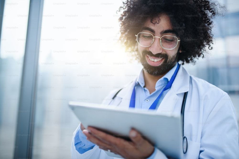 Porträt eines fröhlichen männlichen Arztes mit Tablette, der im Krankenhaus steht. Speicherplatz kopieren.