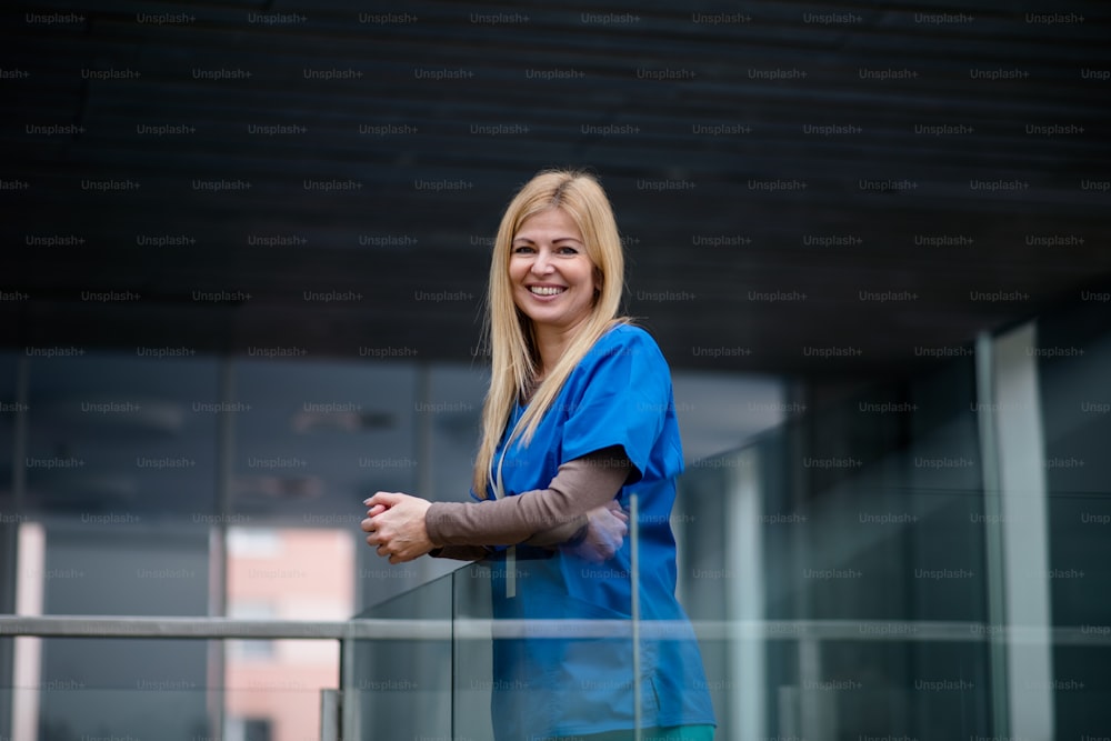 Portrait of doctor standing in hospital , leaning on glass railing. Copy space.