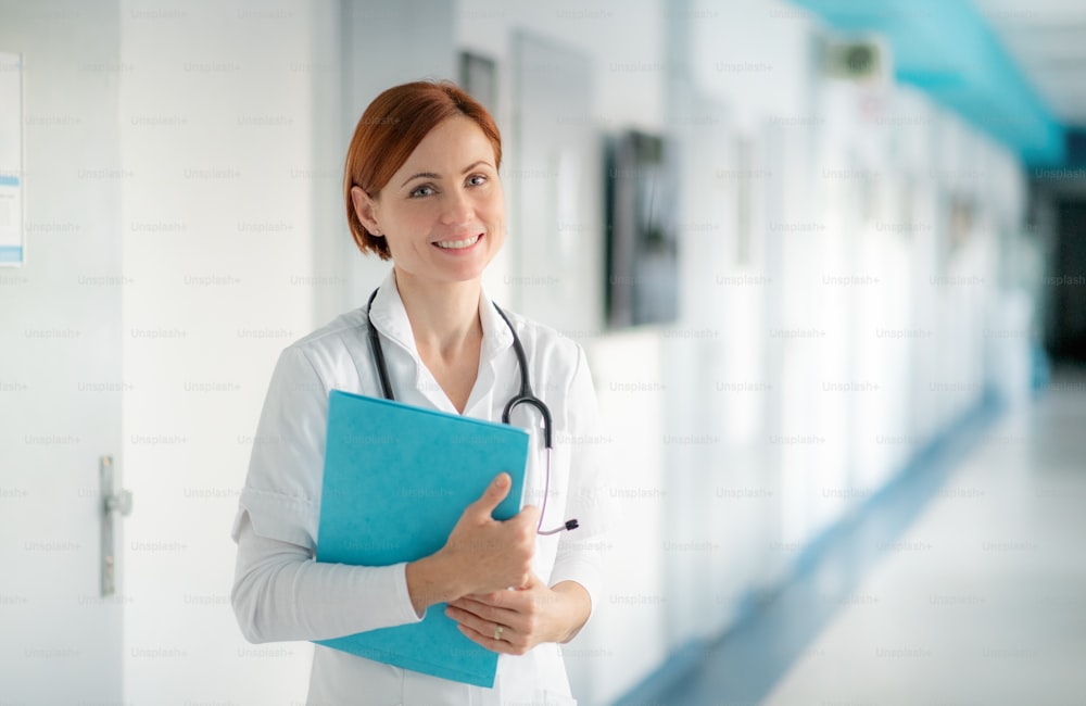 Portrait of woman doctor with clipboard standing in hospital. Copy space.