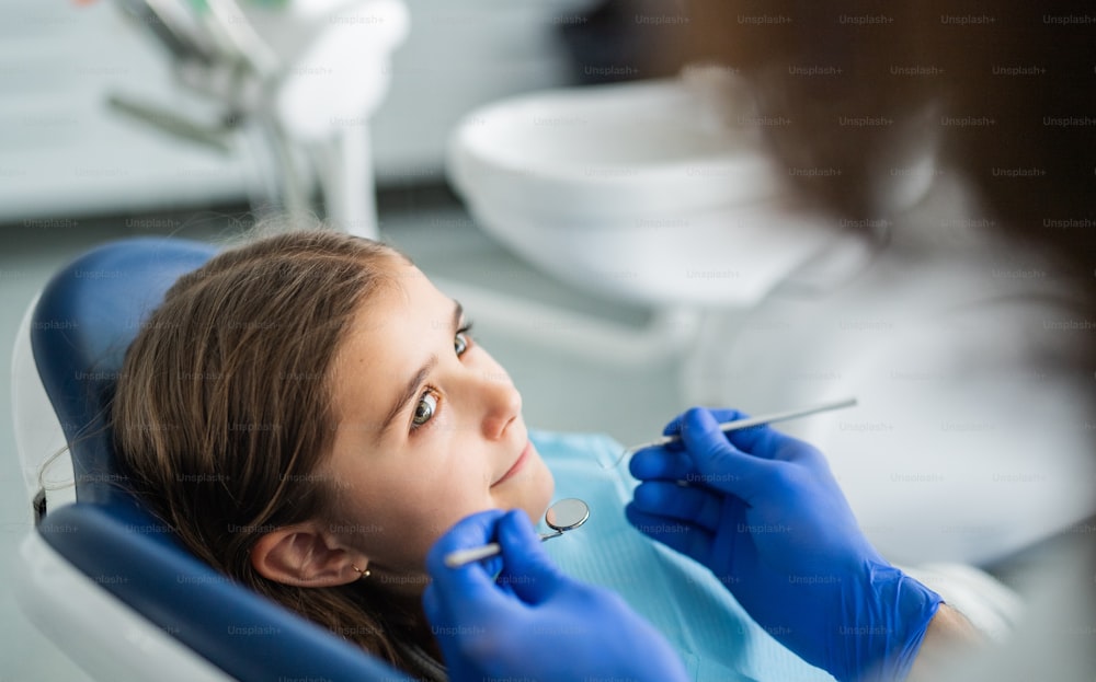 Annual dental check-up of small child girl in dentist surgery.