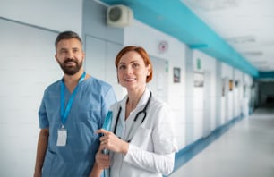 Porträt eines Mannes und einer Ärztin, die im Krankenhaus spazieren gehen und in die Kamera schauen. Speicherplatz kopieren.