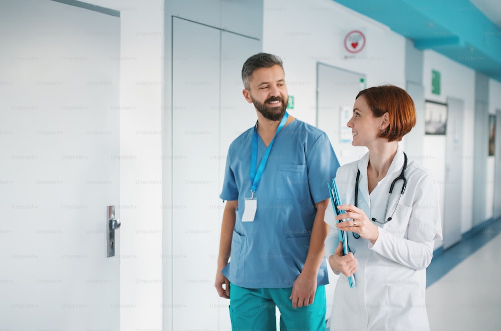 Portrait of man and woman doctor walking in hospital, talking. Copy space.