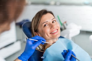 Uma mulher tem um check-up odontológico anual em cirurgia de dentista.