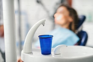 Close-up of blue plastic cup in dentist surgery, annual check-up concept.