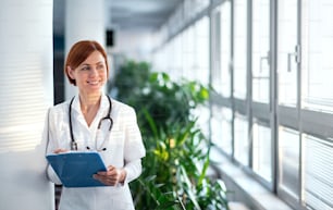 Portrait of woman doctor with clipboard standing in hospital. Copy space.