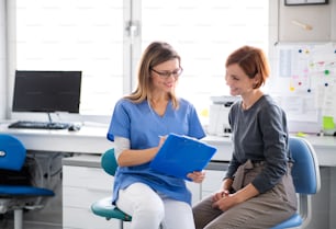 Ein Zahnarzt mit Tablette spricht mit einer Frau in einer Zahnarztpraxis, einer zahnärztlichen Untersuchung.