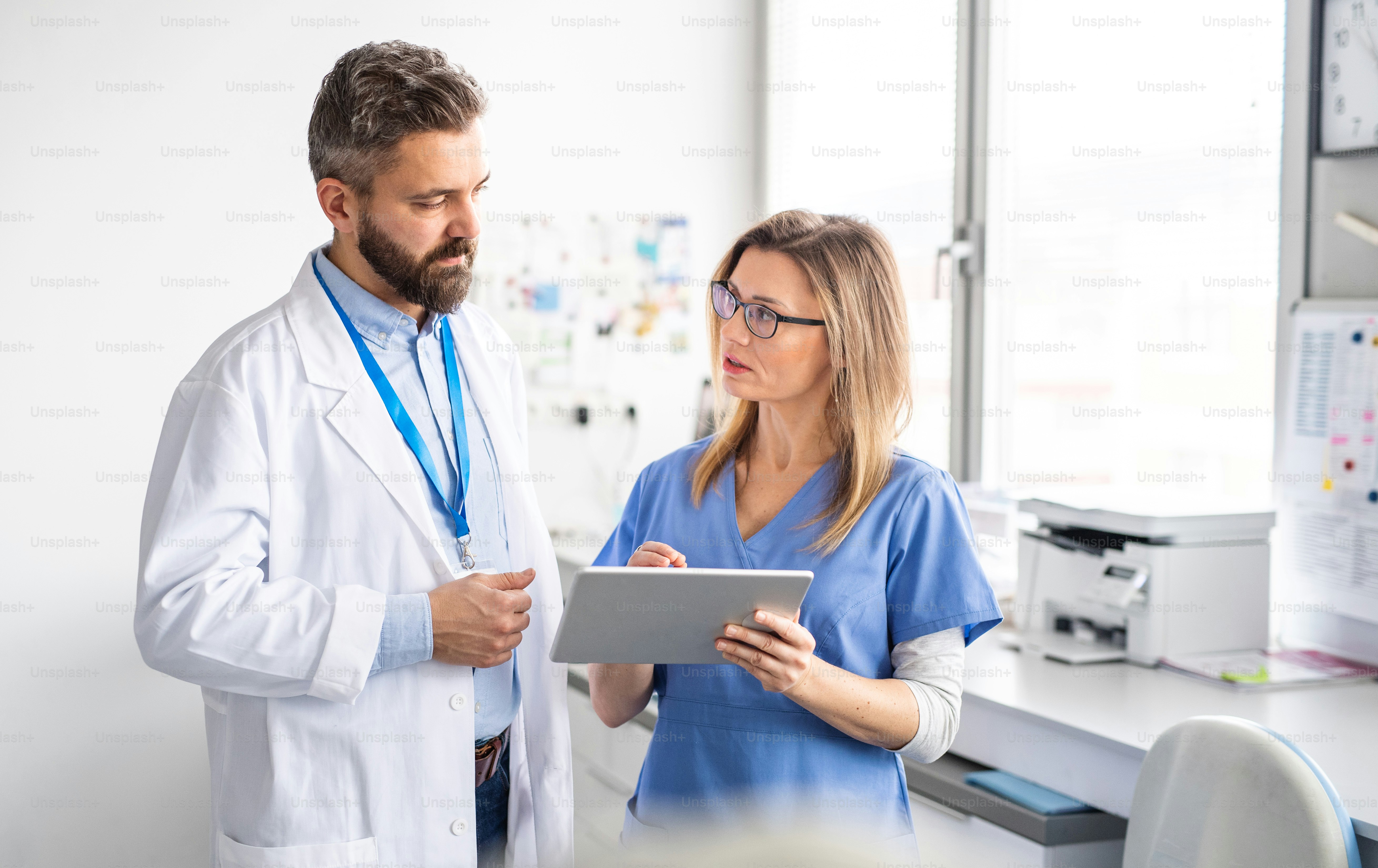 Un retrato frontal del asistente dental y el dentista en la cirugía dental moderna, usando tableta.