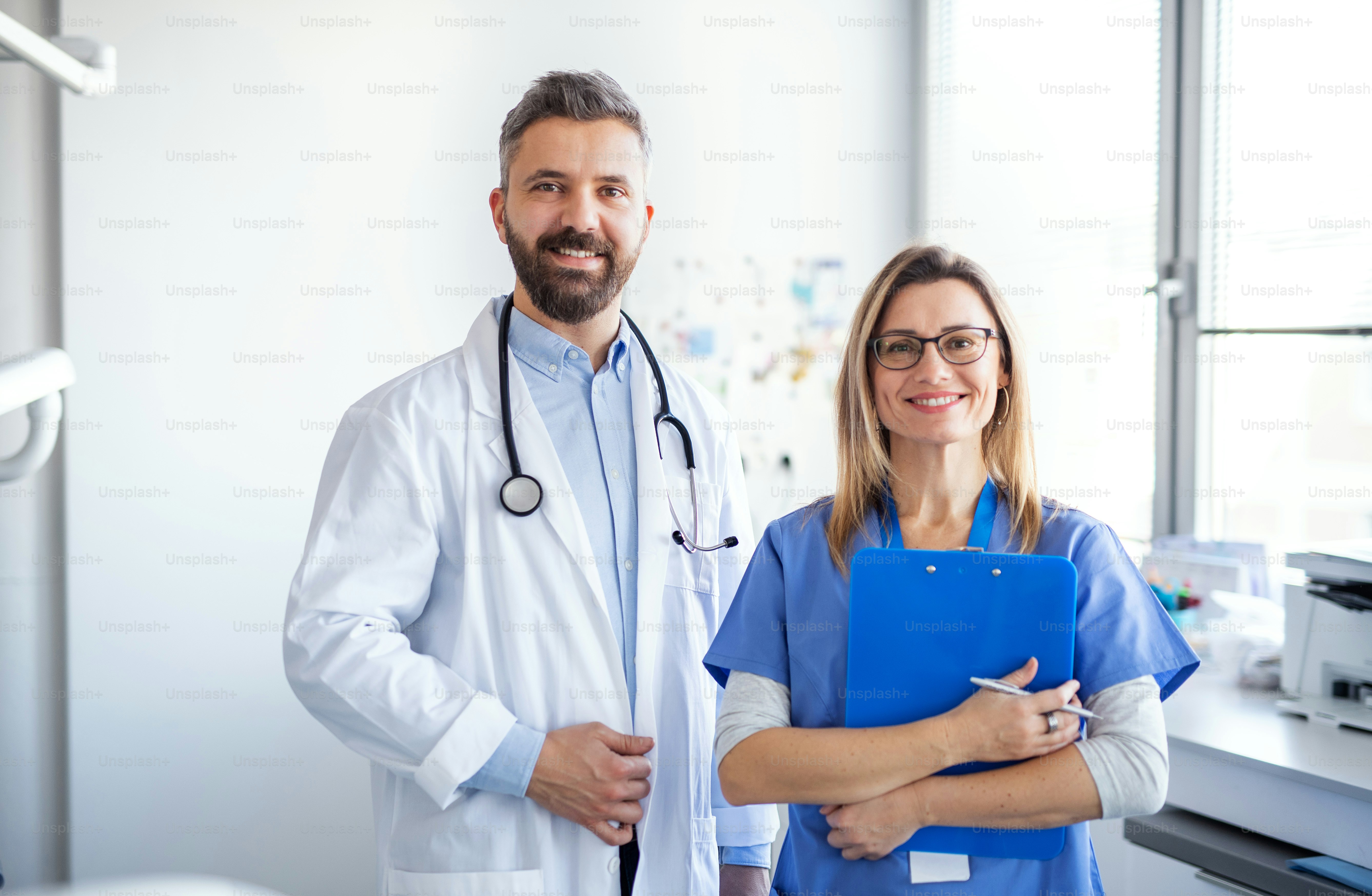 Un portrait de face de l’assistant dentaire et du dentiste en chirurgie dentaire moderne, regardant la caméra.