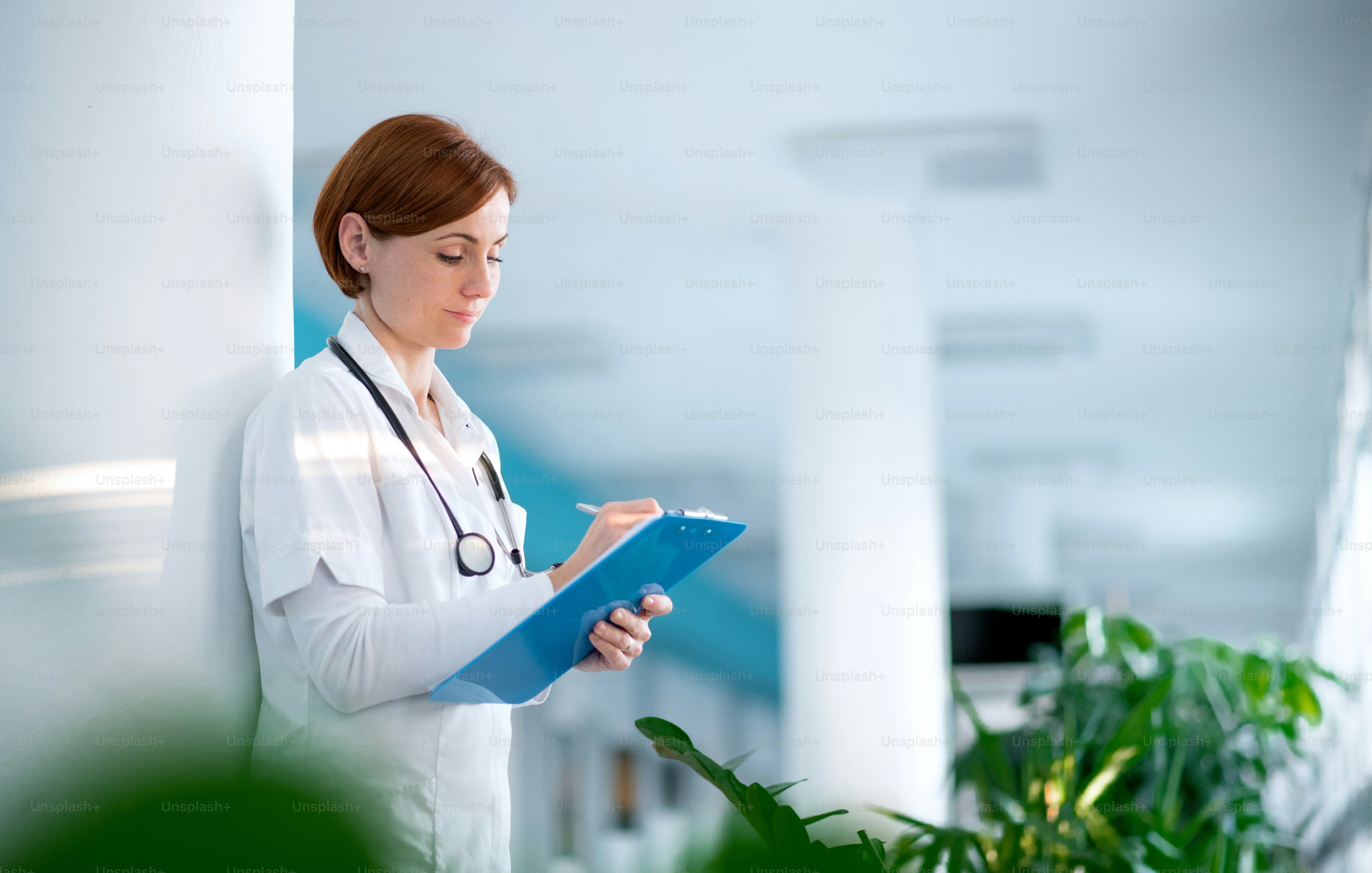 Portrait of woman doctor with clipboard standing in hospital. Copy ...