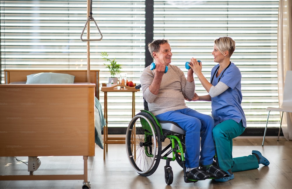 Un operatore sanitario e paziente anziano in ospedale, concetto di fisioterapia.