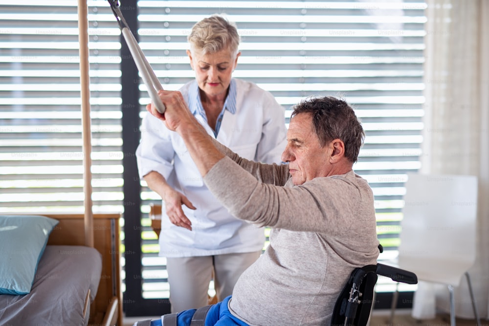 병원에서 휠체어를 탄 마비된 노인 환자를 돕는 의료 종사자.