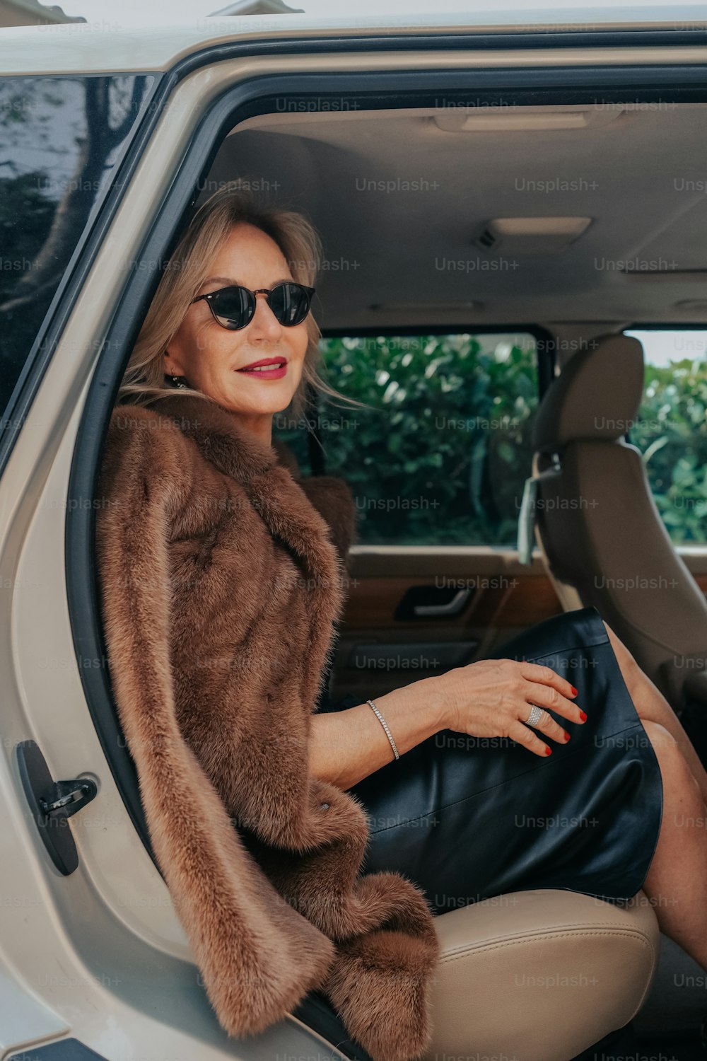 a woman in a fur coat sitting in a car