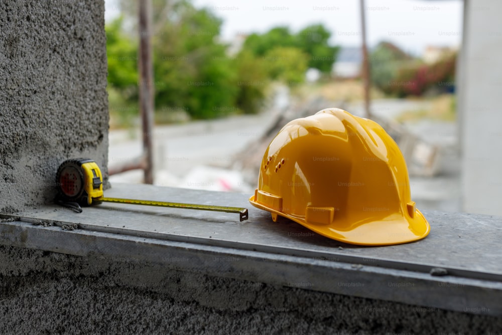 a yellow hard hat sitting on top of a cement wall