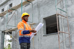 a man in a hard hat and safety vest holding a blueprint