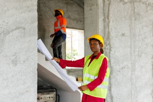 a woman in a yellow safety vest holding a blueprint