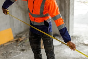 a man in an orange safety jacket holding a measuring tape