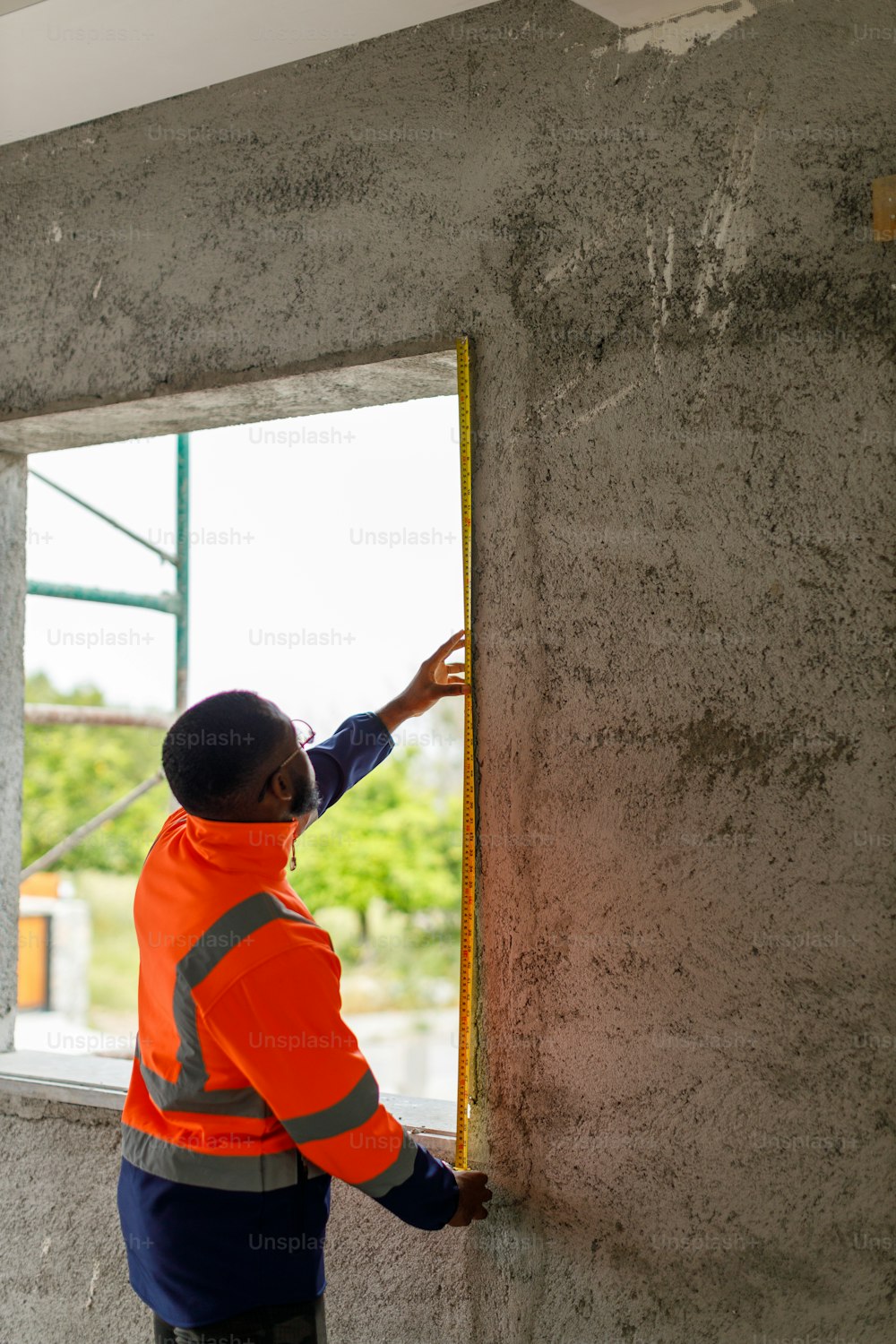 a man in an orange safety vest working on a window