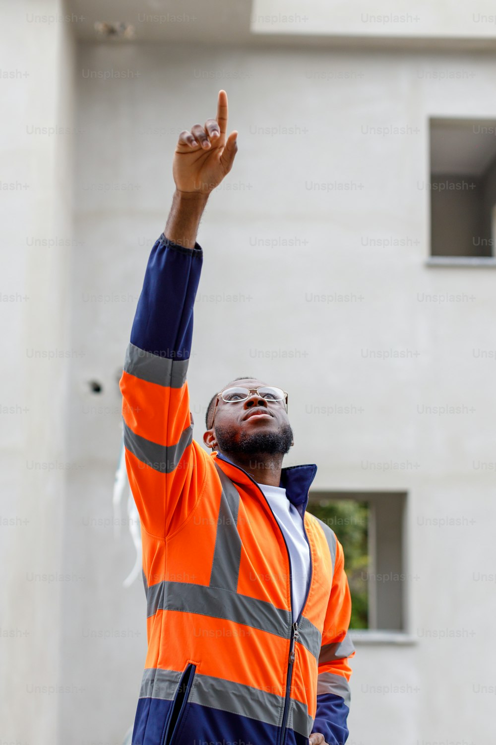 Un uomo con una giacca arancione e blu che alza la mano
