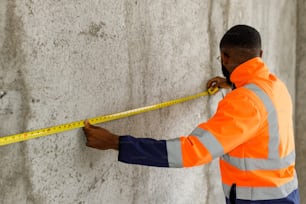 a man measuring a wall with a tape
