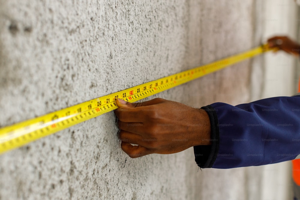 une personne mesurant un mur avec un ruban adhésif