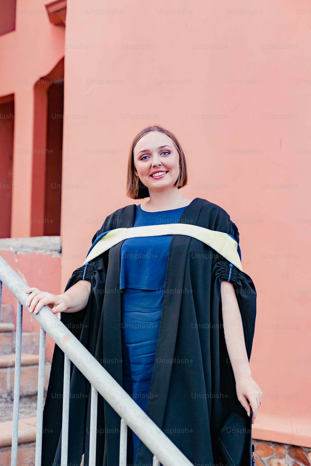 a woman in a graduation gown standing on a stair case