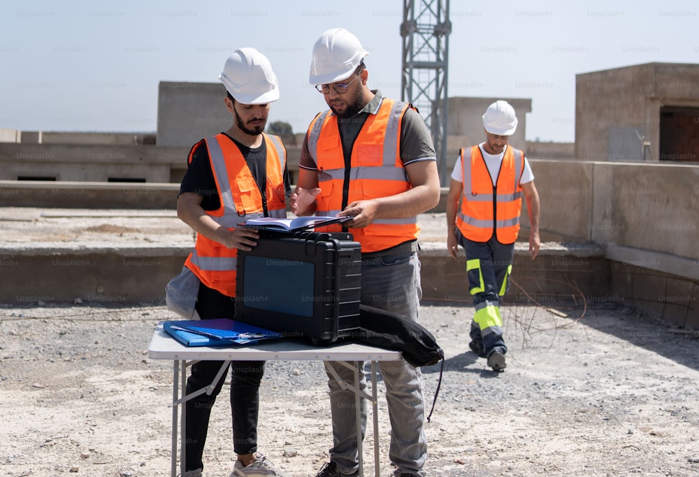 two men in safety vests looking at a computer