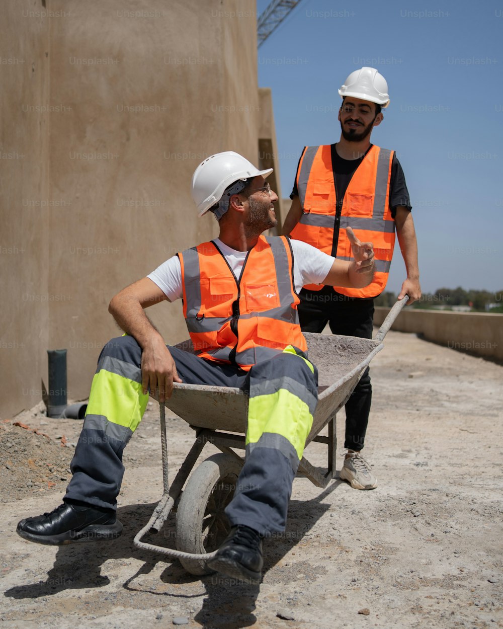 two construction workers sitting on a wheelbarrow