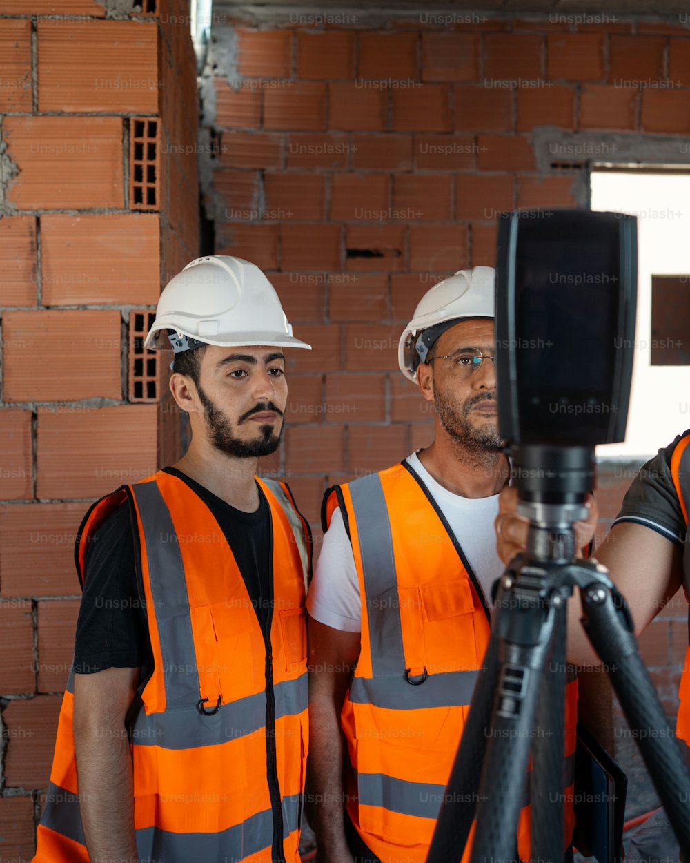 Tre operai edili in piedi davanti a una telecamera