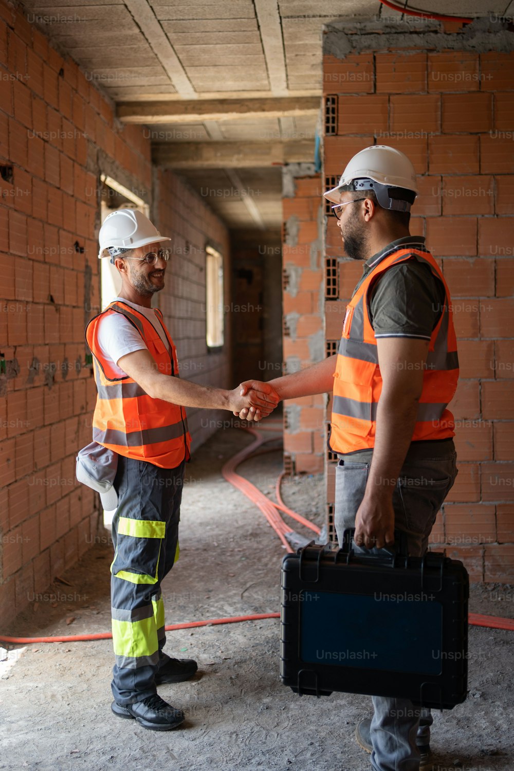 two construction workers shaking hands in a building