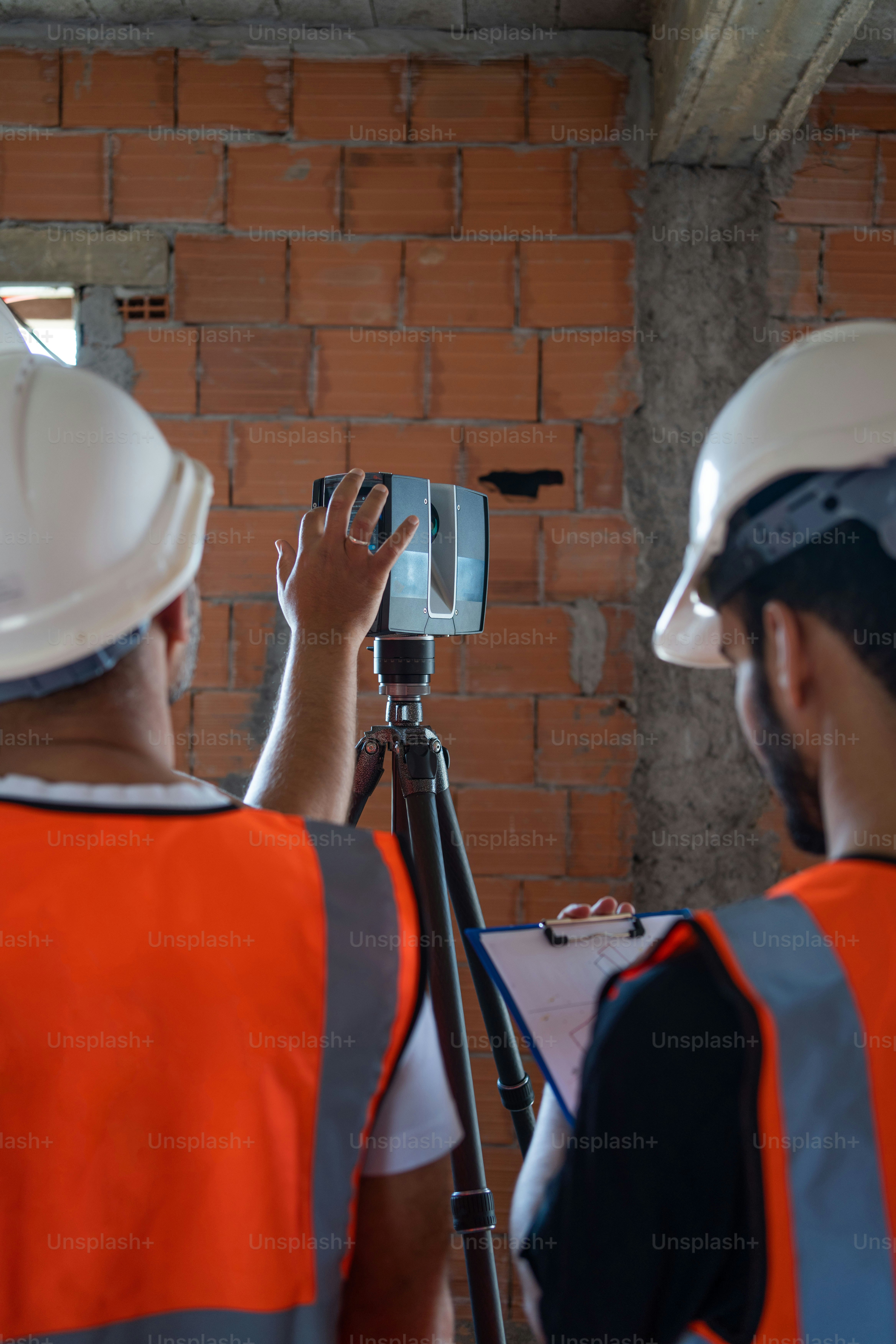 a couple of men standing next to each other in front of a brick wall